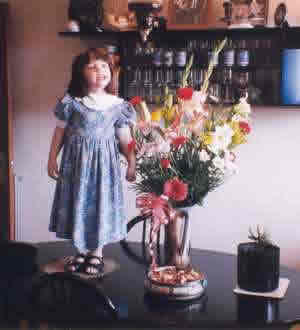 Niña y florero encima de la mesa.