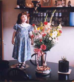 Menina e vaso em cima da mesa.